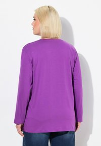 Langärmliges lila Shirt aus weichem Stoff, mit Rundhalsausschnitt und lockerem Schnitt, in schlichter Ausführung und ohne sichtbare Muster.