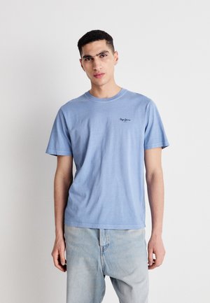 Ανοιχτό μπλε βαμβακερή μπλούζα με κοντά μανίκια, στρογγυλή λαιμόκοψη και ένα μικρό μαύρο λογότυπο στο αριστερό στήθος. Συνδυάστε με ανοιχτό μπλε τζιν.