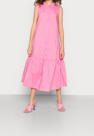 Růžové midi šaty bez rukávů s volánovým límcem a zapínáním na knoflíky vpředu, nošené s růžovými sandály na podpatku na neutrálním pozadí.