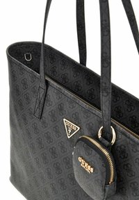 Black tote bag with textured exterior, featuring a gold-tone logo plaque and a small zippered pouch. Dual flat handles for carrying.