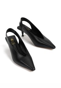 Czarne skórzane czółenka na ramiączku z szpiczastym noskiem, o zaokrąglonym kształcie i małym, cienkim obcasie. Posiadają subtelny elastyczny detal z tyłu.