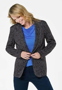 Marineblazer met een gestructureerd patroon, voorzien van een getailleerd ontwerp, inkepingen op de revers en knoopsluiting, over een blauwe top heen.