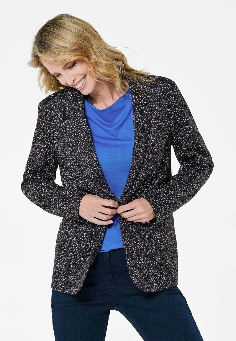 Marineblazer met een gestructureerd patroon, voorzien van een getailleerd ontwerp, inkepingen op de revers en knoopsluiting, over een blauwe top heen.