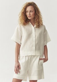 Witte linnen short-sleeve overhemd met een boxy pasvorm en een ronde zoom, gecombineerd met bijpassende shorts met een relaxte pasvorm en zijzakken.