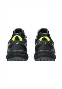 Baskets de course noires avec des accents jaunes néon, tige en maille et synthétique, semelles texturées, col rembourré et talon renforcé pour la stabilité.