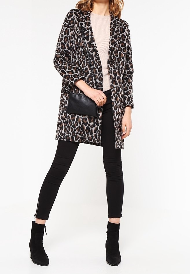 Leopardmönstrad kappa med avslappnad passform, långa ärmar och en framficka, kombinerad med svarta leggings och ankelskor. Mjukt, texturerat tyg.