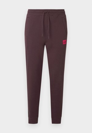 Dark brown sweatpants with a drawstring waist, tapered legs, side pockets, and a small red logo patch on the front. Soft, smooth fabric.