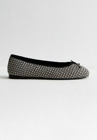 Ballet flats a fantasia bianco e nero, superiore in tessuto, punta arrotondata, accentuate da un piccolo fiocco davanti, suola piatta e texture liscia.
