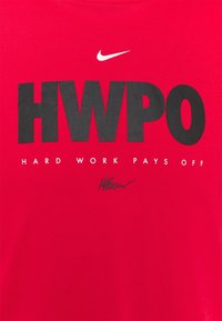 Camiseta roja de Nike con grandes letras negras que dicen "HWPO", la frase más pequeña "Hard Work Pays Off" debajo, y una firma estilizada en la parte inferior.