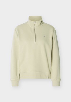 Lysebeige quarter-zip pullover med opretstående krave, ribkant ved ærmer og kant samt lille broderet logo på venstre bryst.