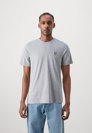 Grå kortärmad t-shirt i bomullstyg med rund halsringning; har en liten gul broderad logotyp på vänster bröst.