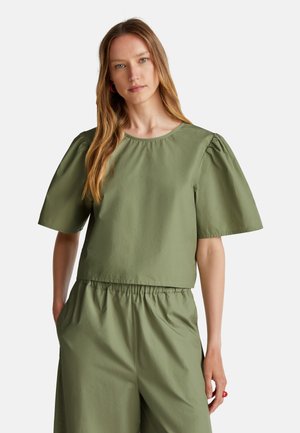 Top corto de manga corta en suave tela color verde oliva. Cuenta con un escote redondo y mangas abullonadas, acompañado de pantalones holgados a juego.
