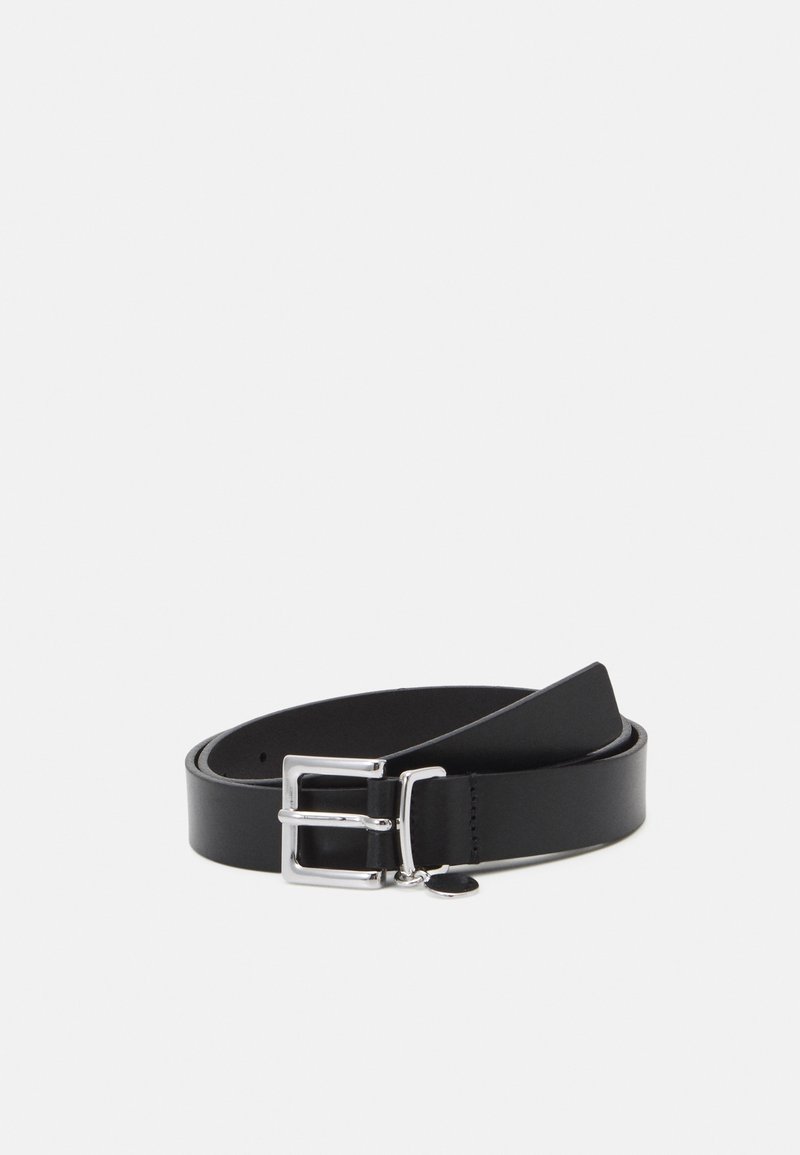 Ceinture en cuir noir roulée avec une boucle rectangulaire argentée brillante et un petit pendentif métallique attaché sur un fond clair uni.