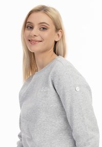 Lichtgrijze sweater met een ronde hals, zachte textuur, voorzien van een klein ankerlogo en een knoopaccent op de mouw.