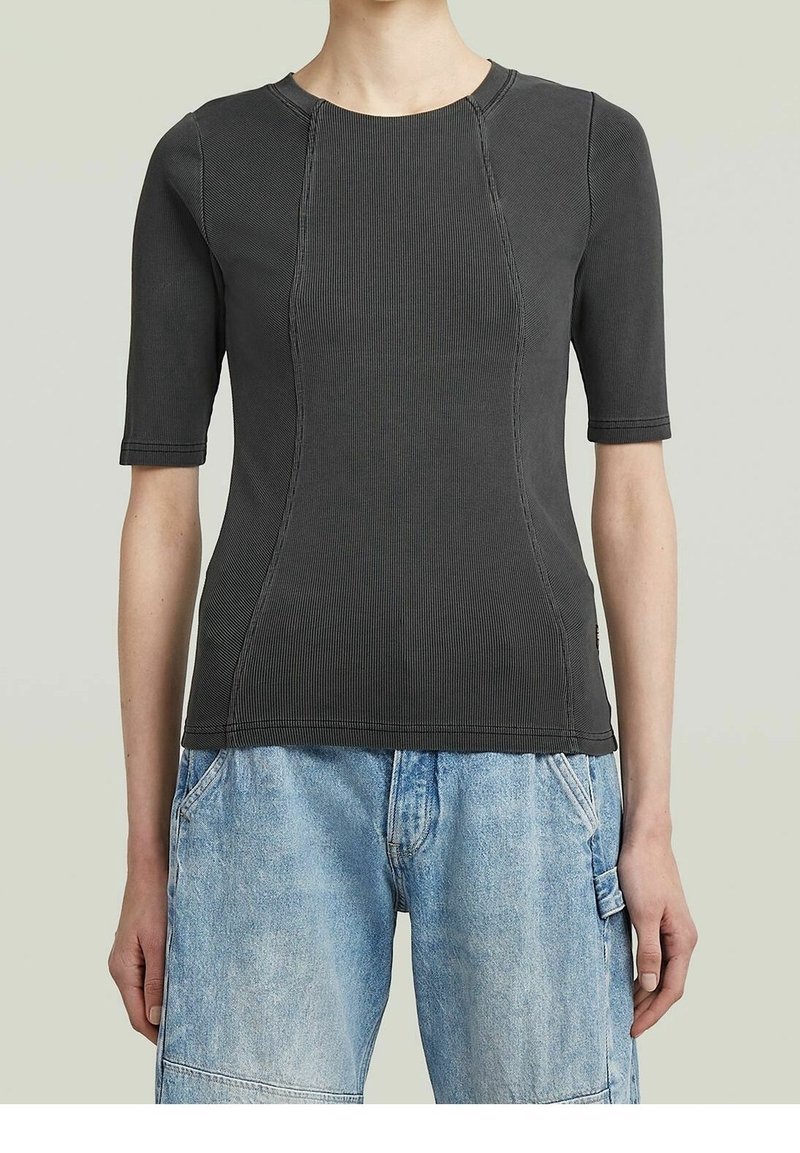 Personne portant un haut cintré gris foncé à manches courtes côtelé avec des détails de coutures visibles et un short en denim bleu clair avec poches latérales.