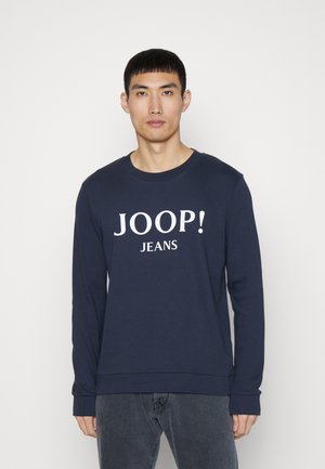 Marineblauwe katoenen sweatshirt met lange mouwen, geribbelde halslijn en een wit 'JOOP! JEANS' logo bedrukt op de voorkant. Zachte textuur.