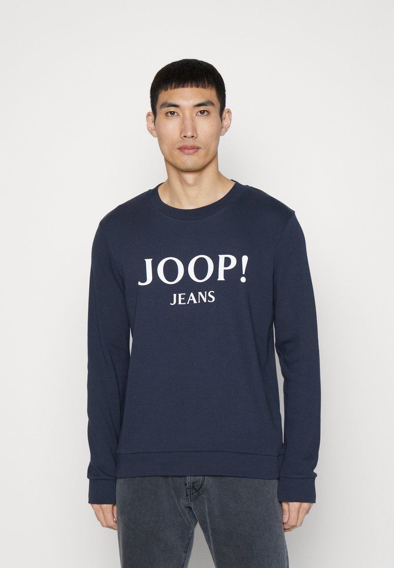 Felpa in cotone blu navy con maniche lunghe, colletto a coste e logo bianco "JOOP! JEANS" stampato sul davanti. Texture morbida.
