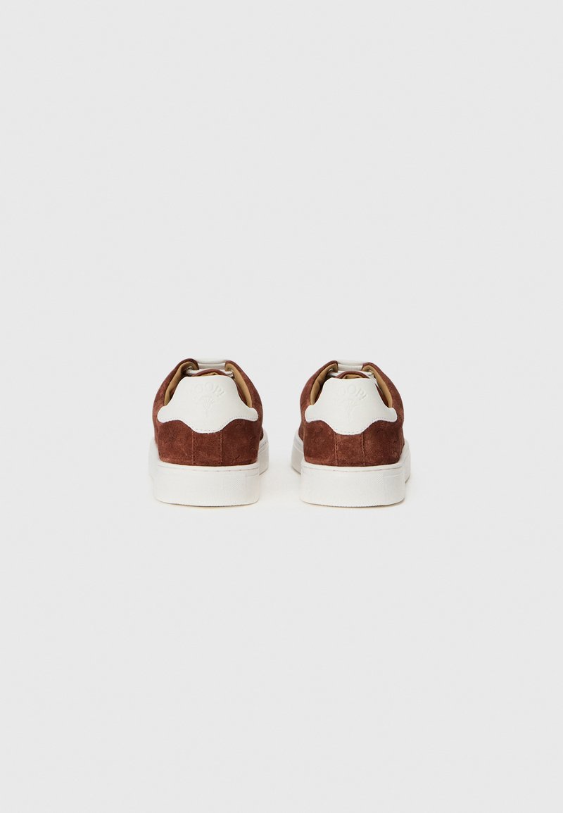 Braune Wildleder-Sneakers mit weißen Gummisohlen, im Low-Cut-Design, runden Fersenlogo und betonter Naht entlang der Rückseite.