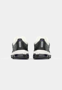 Schwarz-weiße Sneakers mit einem Obermaterial aus Mesh, gepolsterter Sohle und Max Air-Details. Mit lila Akzenten und strukturierten Oberflächen.