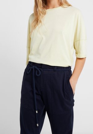 Lichtgele T-shirt met korte mouwen, gecombineerd met marineblauwe broek met trekkoord, zijzakken en een ontspannen pasvorm.