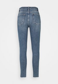 Jeans ajustados en denim azul oscuro con una textura suave. Presentan dos bolsillos traseros y un diseño de cinturilla estándar.