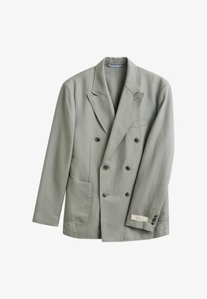 Blazer gris clair croisé avec revers à encoches, devant à quatre boutons, deux poches et une petite étiquette de marque sur le poignet de la manche gauche.