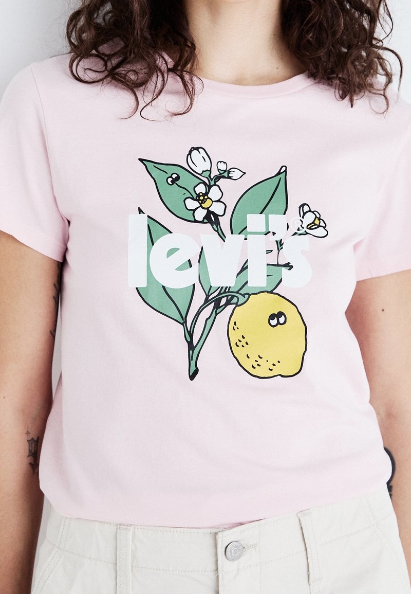 Rosa Baumwoll-T-Shirt mit einem grafischen Design von einer Zitrone, Blättern und Blumen, versehen mit dem Text "levi's" in fetter weißer Schrift.