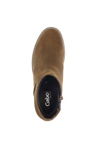 Botte de cheville en daim marron avec bout arrondi, fermeture éclair latérale, surpiqûre blanche le long de la semelle et texture douce. L'intérieur présente un détail du logo de la marque.