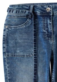 Jean en denim bleu avec un lavage délavé, poche avant visible, passants de ceinture et fermeture par bouton métallique à la taille.