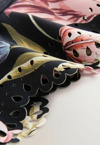 Cvjetni materijal s crnom pozadinom; sadrži dekorativne valovite rubove s izrezbarenim dizajnima i živopisne, detaljne cvjetne uzorke u pastelnim bojama.