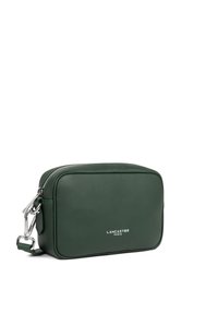 Borsa a tracolla verde in pelle con forma rettangolare, accessori in argento, chiusura con zip e logo sulla parte anteriore. Texture liscia.