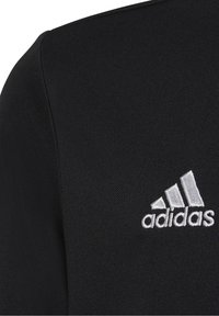 Svart sporttröja med texturerad tyg, korta ärmar och en vit broderad Adidas-logga på vänster bröst.