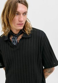 Black knitted polo shirt with vertical stripes, featuring a V-neck and short sleeves. Accompanied by a black bandana around the neck.