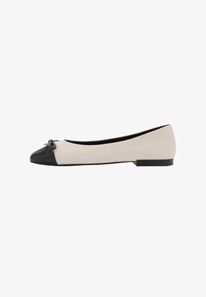 Chaussure plate pour femmes avec un corps beige, un bout noir, un petit nœud noir et un petit talon noir, présentée en profil latéral.