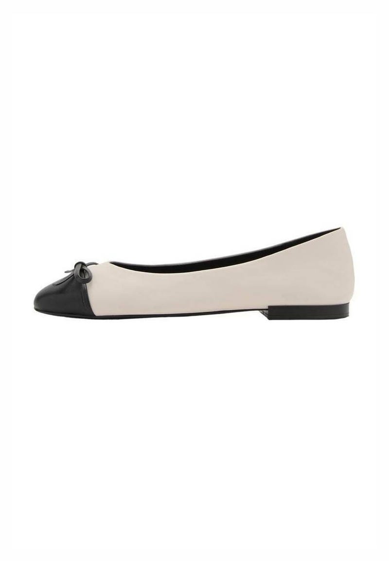Zapato plano de mujer con cuerpo beige, punta negra, pequeño lazo negro y tacón bajo negro, mostrado en perfil lateral.