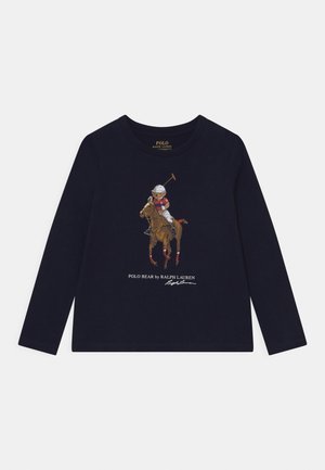 Navyblå langærmet skjorte med grafik af en bjørn, der spiller polo til hest, mærket "Polo Bear by Ralph Lauren" med underskrift nedenunder.