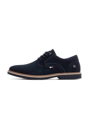 Zapatos de ante azul marino con cordones y una suela de color marrón claro contrastante, con detalles de costura y un pequeño logo en el lateral.