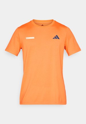 Oranžna bombažna majica s krožnim izrezom, na sprednjem delu z belim napisom "TENNIS" in temno modrim logotipom znamke Adidas na prsih.