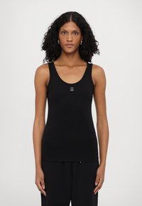 Top senza maniche nero con scollatura rotonda e una piccola etichetta con logo al centro. Tessuto morbido e elasticizzato con un design aderente.