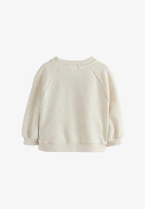 Gai bēšs džemperis ar krāsainiem plankumiem, ribota apkakle un pārlieku lielas piedurknes. Tam ir vienkāršs, ikdienišķs dizains un teksturēta auduma.