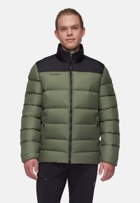 Grön puffjacka med svart övre del och hög krage, med dragkedja framtill och logotypdetalj på bröstet. Slät, quiltad textur.