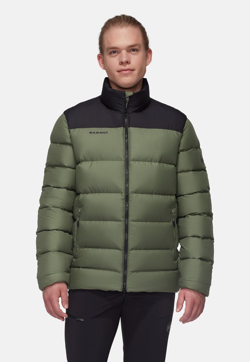 Grön puffjacka med svart övre del och hög krage, med dragkedja framtill och logotypdetalj på bröstet. Slät, quiltad textur.