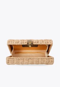 Clutch in paglia intrecciata con una chiusura in metallo dorato che presenta un design decorativo a forma di uccello. Interno foderato in morbido tessuto dorato con dettagli a strisce.