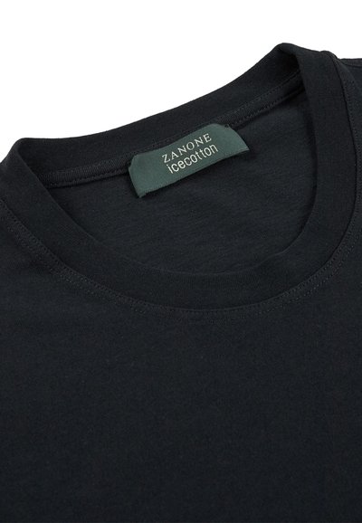 La camiseta de algodón negra presenta un escote redondo y una etiqueta que dice "ZANONE icecotton". La tela parece suave con una textura uniforme.