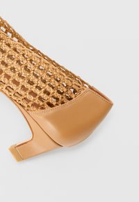 Beige korkokengät, joissa on kudottu päällinen ja sileä nahkakorko. Korko on suorakulmainen ja lohkotyyppinen.