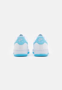 Fehér Nike Air sportcipők világoskék kiegészítőkkel. Simas bőr felsőrésze, párnázott bokarésze és mintás gumitalpa van.