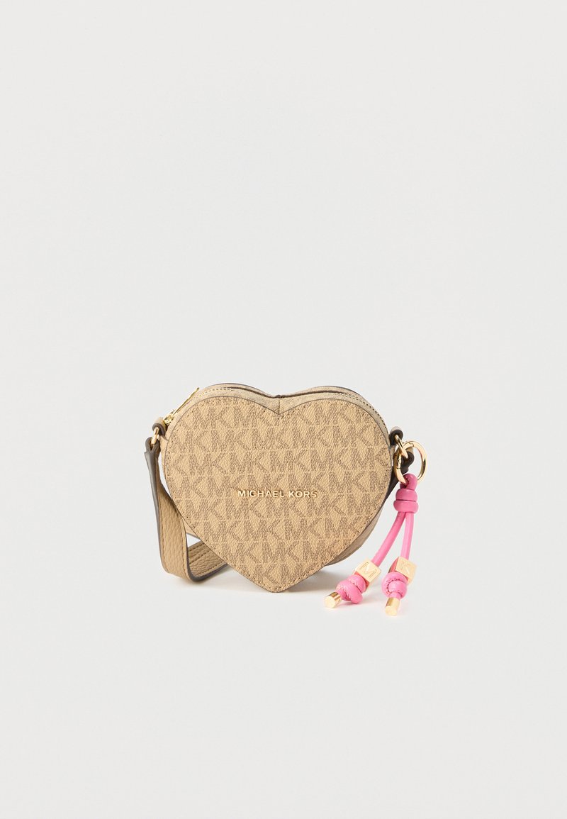 Τσαντάκι χιαστί σε σχήμα καρδιάς σε μπεζ χρώμα με λογότυπο Michael Kors, ροζ δερμάτινα κρόσσια και υφή με σχέδια σε απλό φόντο.