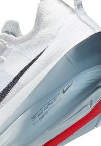 Nike Road Racing AF shoes, featuring a white knit upper, black swoosh, and grey midsole with red outsole. Textured surface, lightweight design.