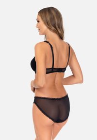 Czarny zestaw bielizny składający się z gładkiego, nieusztywnianego biustonosza z regulowanymi ramiączkami oraz dopasowanych, przezroczystych majtek z falbankami na brzegach.