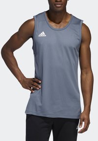 Šedý sportovní tílko vyrobené z texturované tkaniny, s kulatým výstřihem a bílým logem Adidas na levé části hrudníku.